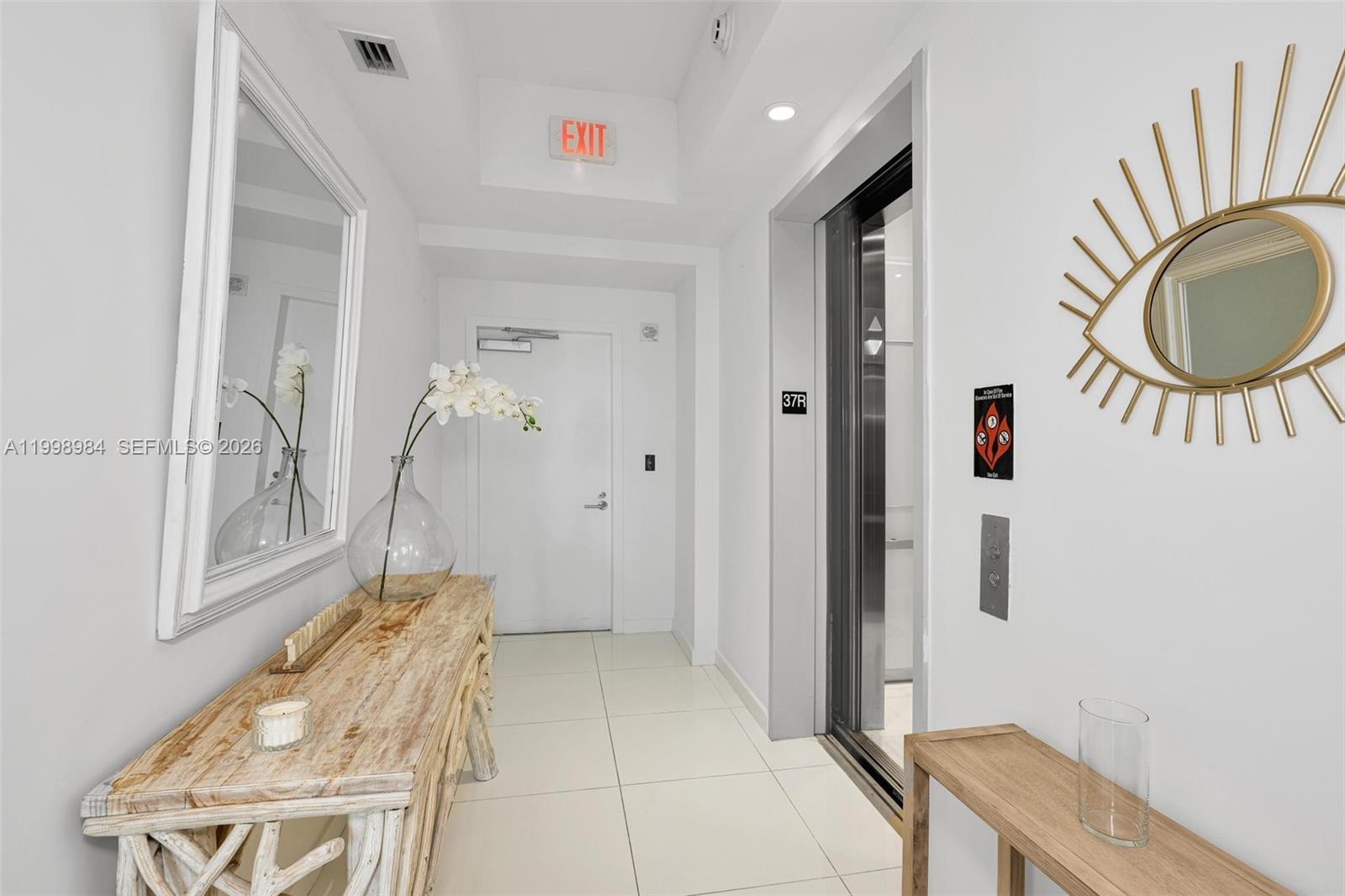 A white-tiled elevator lobby features a rustic wooden console table, a mirror, and wall decor — 851 NE 1st Ave # 3708, Miami FL 33132, MIAMI, FL