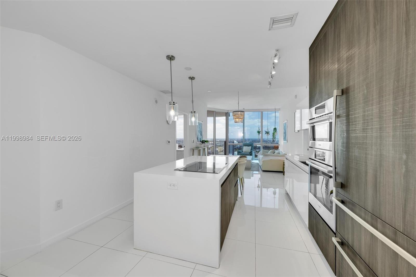 A modern kitchen features a white island, stainless steel appliances, and glossy tile flooring — 851 NE 1st Ave # 3708, Miami FL 33132, MIAMI, FL