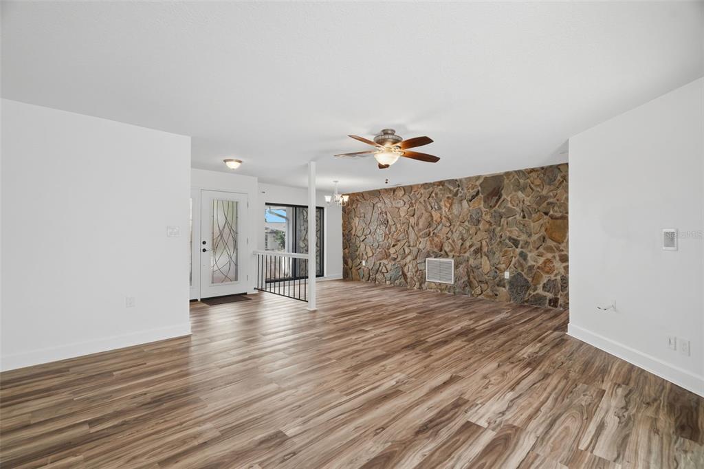 A living room features wood-look flooring, a stone accent wall, and a ceiling fan — 104 NESTLEBRANCH DRIVE, SAFETY HARBOR, FL