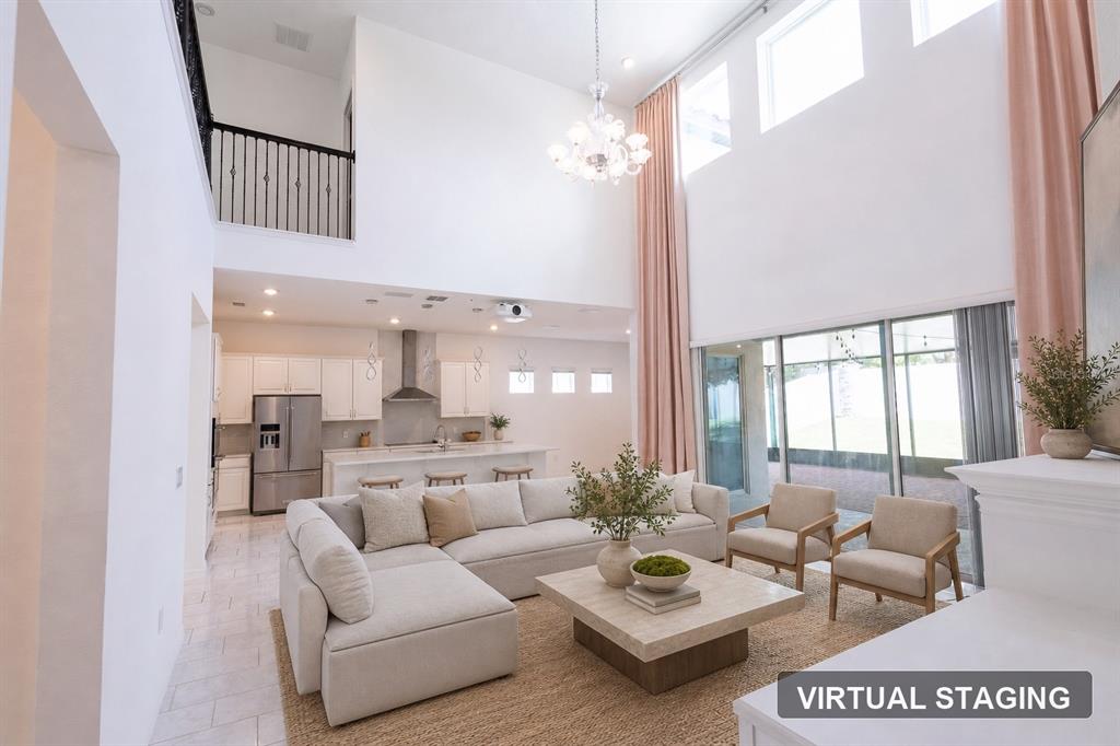 A living room with high ceilings, a sectional sofa, and an open kitchen area — 9567 MEADOW HUNT WAY, WINTER GARDEN, FL