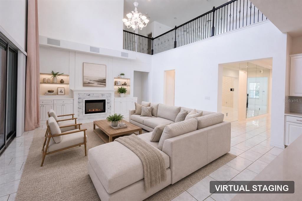 A living room with a fireplace, high ceilings, a balcony, and virtual staging furniture — 9567 MEADOW HUNT WAY, WINTER GARDEN, FL