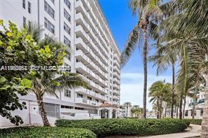 A multi-story white residential building stands behind a landscaped lawn with palm trees — 9195 Collins Ave # 614, Surfside FL 33154, SURFSIDE, FL