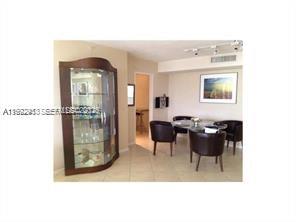 A dining area features a glass display cabinet, a round table, and four dark chairs — 9195 Collins Ave # 614, Surfside FL 33154, SURFSIDE, FL