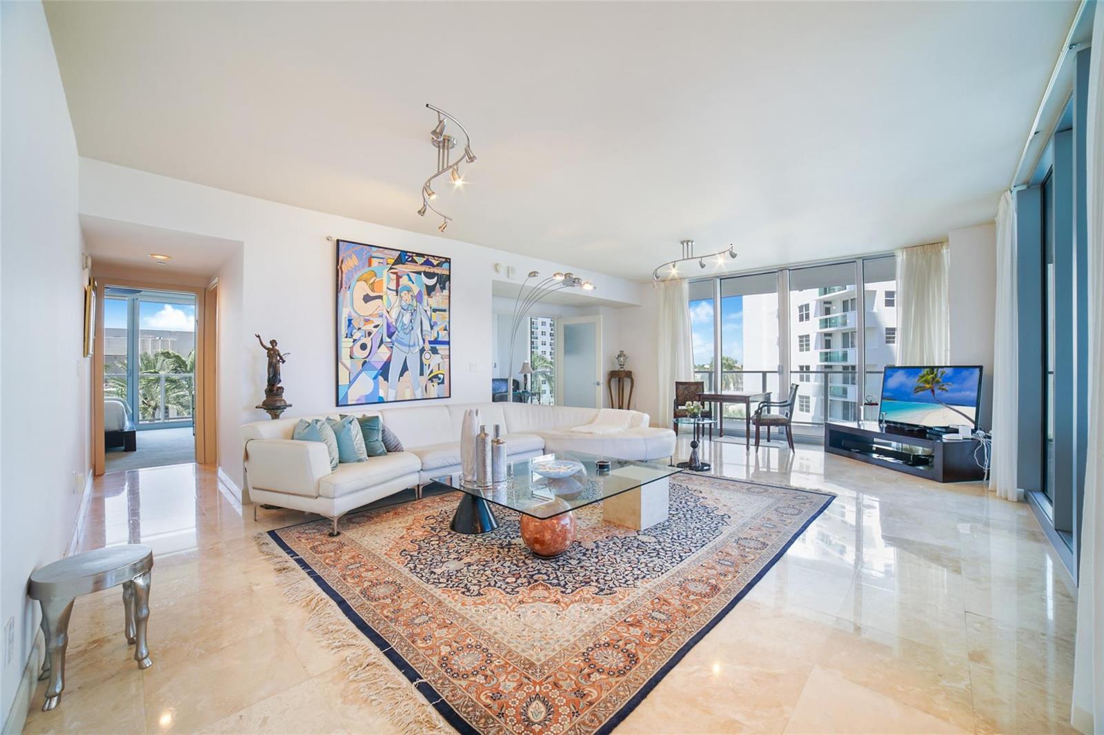 A bright living room features a white sectional sofa, glass coffee table, and patterned rug — 3101 S Ocean Drive # 401, Hollywood FL 33019, HOLLYWOOD, FL