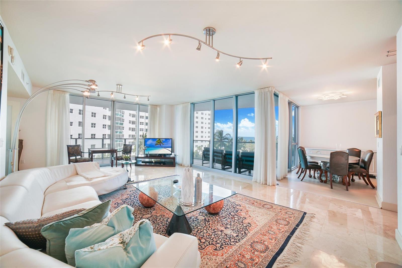 A bright living and dining area with marble floors, floor-to-ceiling windows, and ocean views — 3101 S Ocean Drive # 401, Hollywood FL 33019, HOLLYWOOD, FL