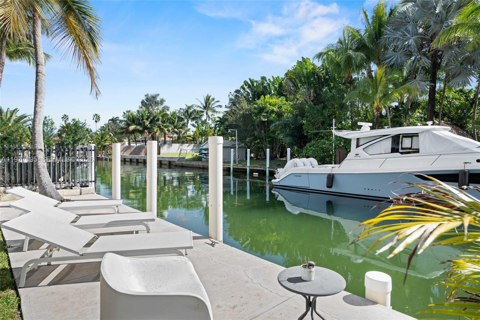 A concrete dock features lounge chairs and a boat moored in a canal — 1028 NE 84th St, Miami FL 33138, MIAMI, FL