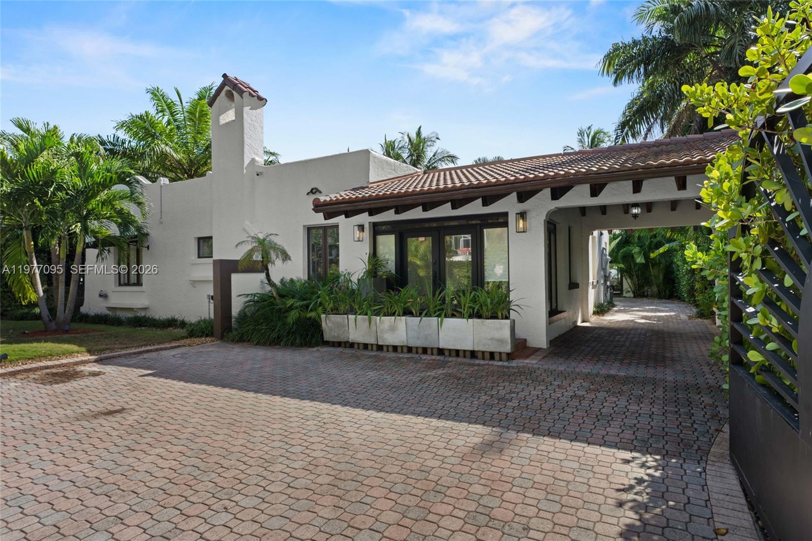 A white stucco house with a tiled roof and a paved driveway under a carport — 1028 NE 84th St, Miami FL 33138, MIAMI, FL