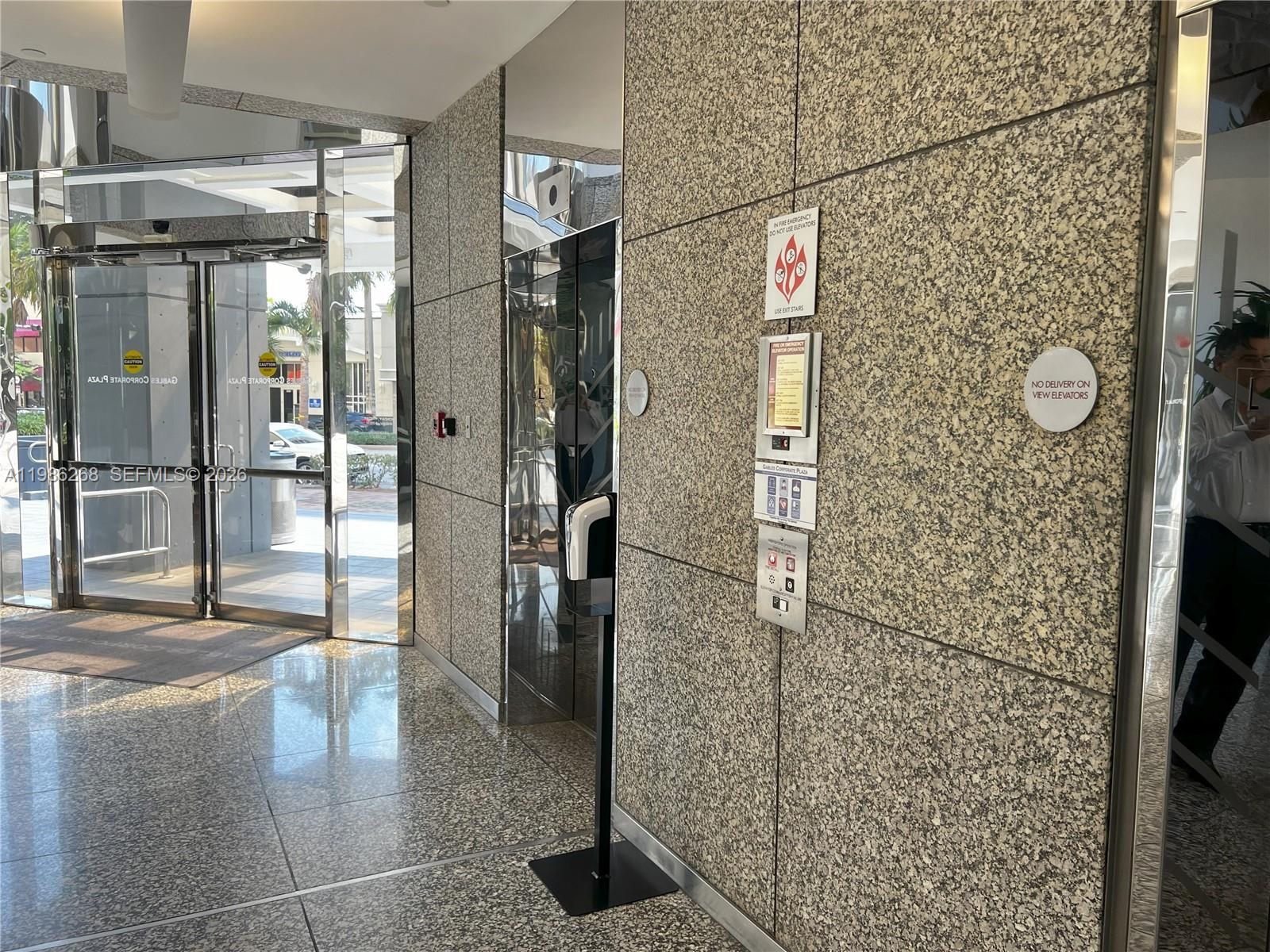 An elevator lobby features granite walls, a hand sanitizer station, and glass entrance doors — 2100 Ponce De Leon Blvd, Coral Gables FL 33134, CORAL GABLES, FL