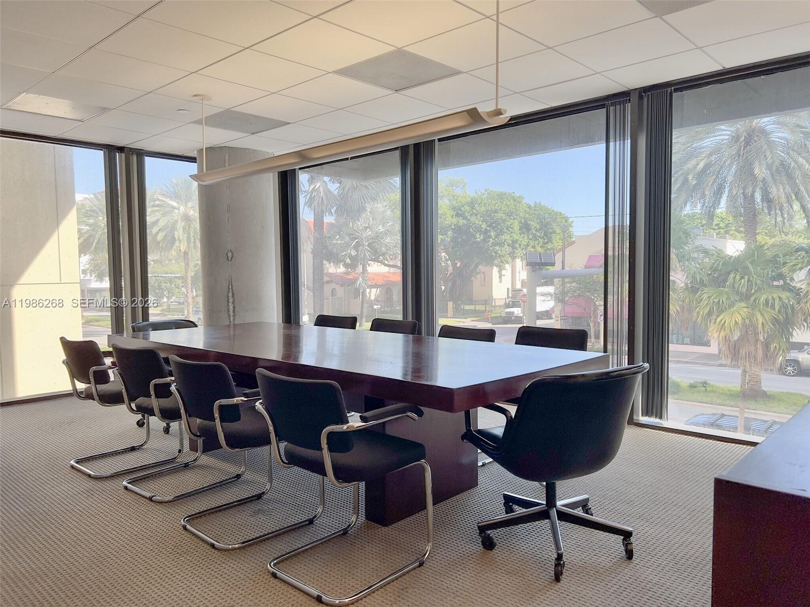 A conference room features a large wooden table, black chairs, and floor-to-ceiling windows — 2100 Ponce De Leon Blvd, Coral Gables FL 33134, CORAL GABLES, FL