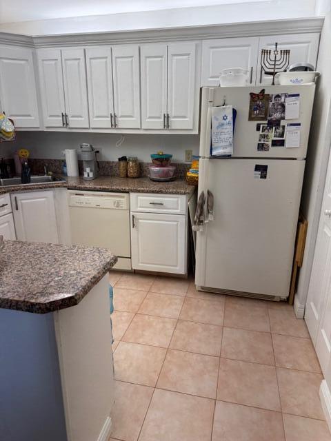 A kitchen features white cabinets, granite countertops, a white refrigerator, and light-colored floor tiles — 440 Pine Glen Lane # 1, FL 33463, FL
