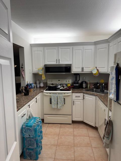 A kitchen features white cabinets, granite countertops, a stainless steel microwave, and a beige stove — 440 Pine Glen Lane # 1, FL 33463, FL