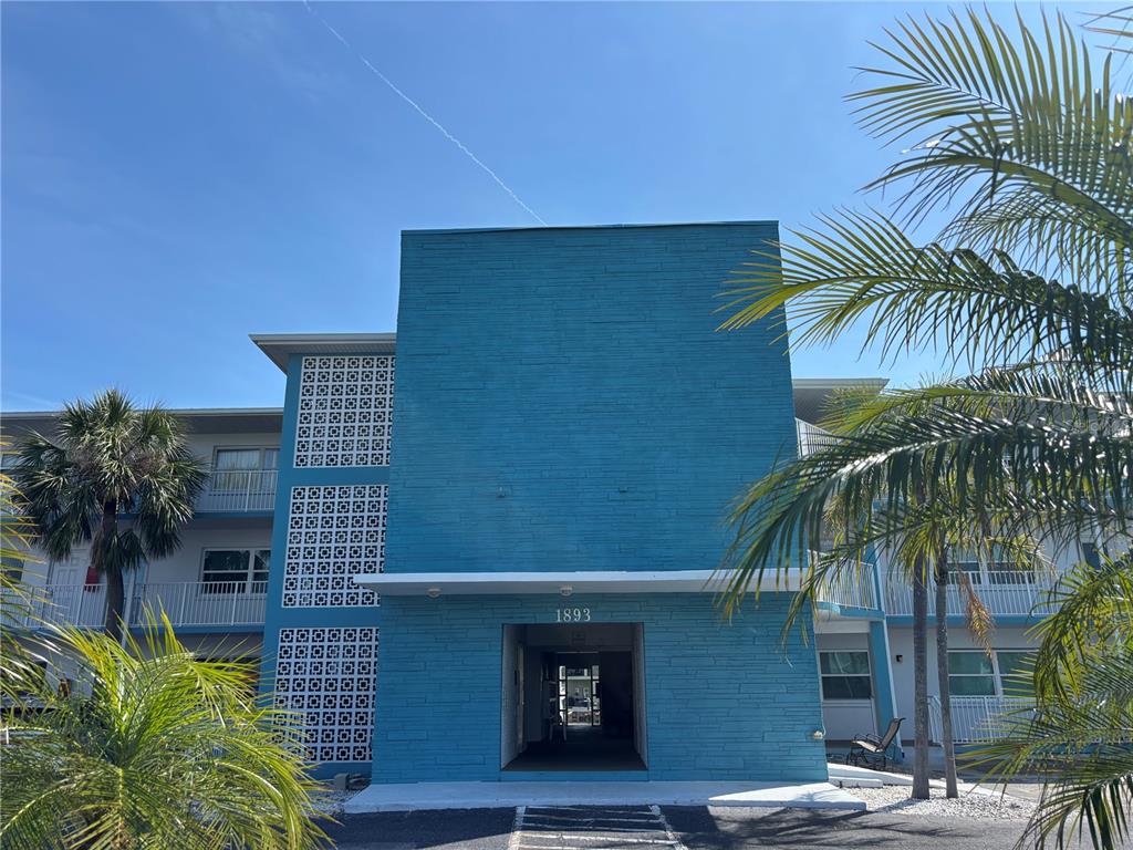 A blue multi-story apartment building features decorative concrete breeze blocks and a central entryway — 1893 SHORE DRIVE S UNIT 114, SOUTH PASADENA, FL