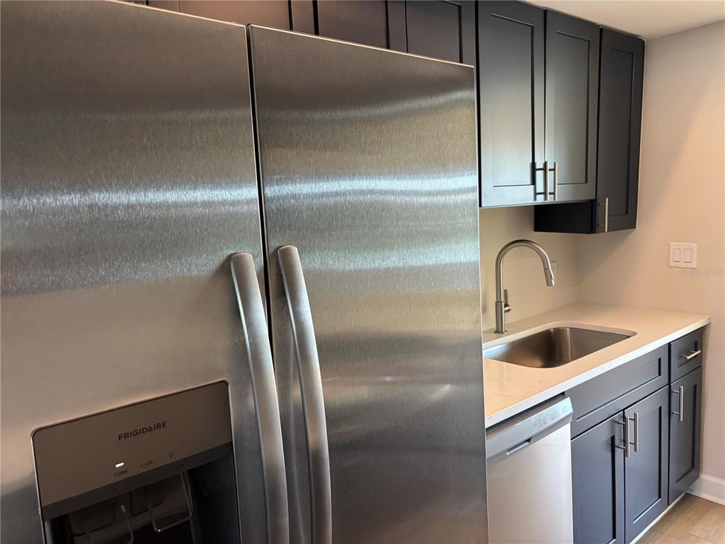 A kitchen features dark cabinets, stainless steel appliances, a white countertop, and a sink — 1893 SHORE DRIVE S UNIT 114, SOUTH PASADENA, FL