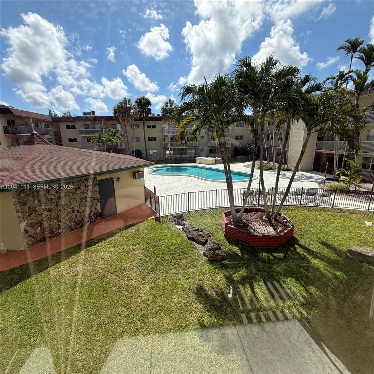 An outdoor view shows a swimming pool, a small building, and palm trees on grass — 7505 SW 82nd St # 206, Miami FL 33143, MIAMI, FL