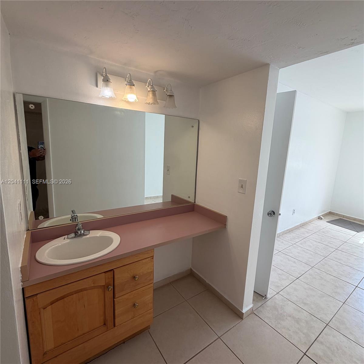 A bathroom vanity features a pink countertop, wooden cabinets, and a large wall-mounted mirror — 7505 SW 82nd St # 206, Miami FL 33143, MIAMI, FL