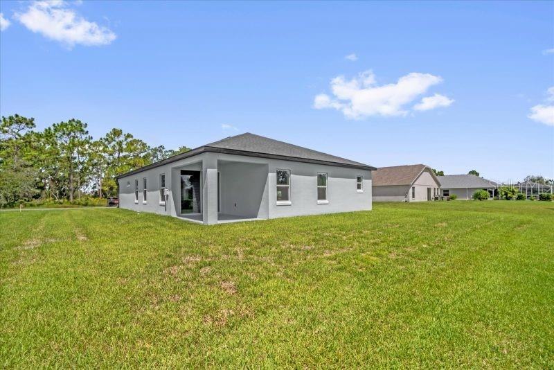 The exterior of a light gray house features a covered patio and a large lawn — 13400 SW 77TH COURT, OCALA, FL