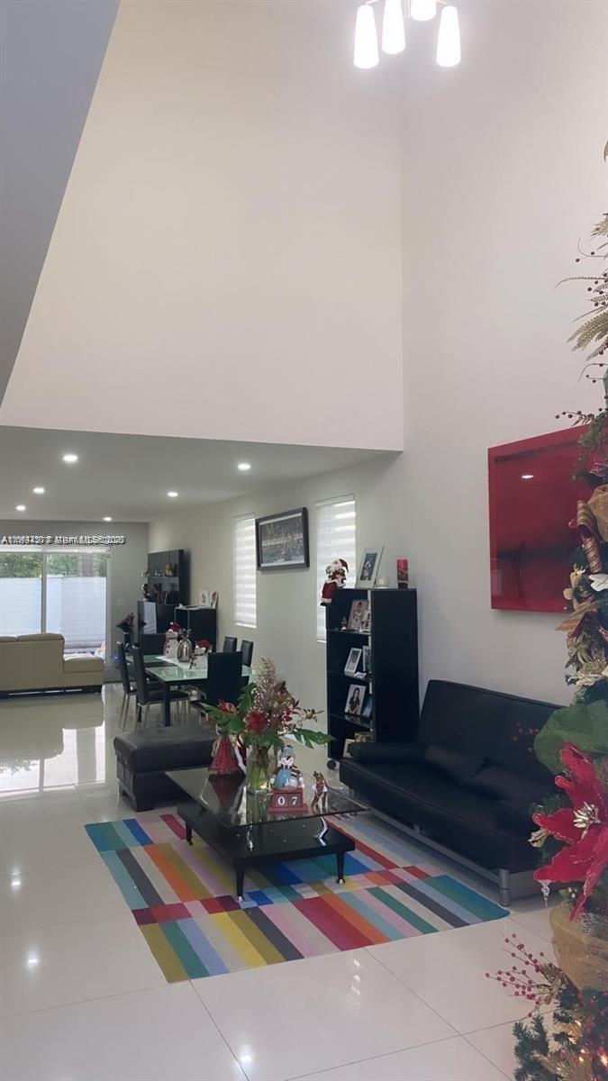 A tall, decorated Christmas tree stands in a bright living room with floor-to-ceiling windows — 9880 NW 74th Ter, Doral FL 33178, DORAL, FL