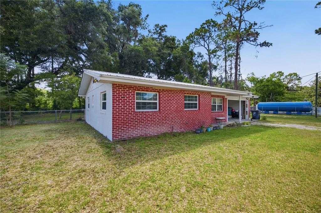 A single-story red brick house with a metal roof sits on a grassy lot — 3416 NE 22ND COURT, OCALA, FL