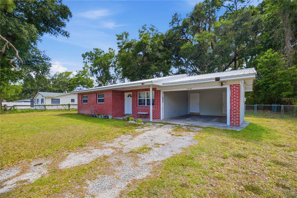 A single-story red brick house features a metal roof and an attached carport — 3416 NE 22ND COURT, OCALA, FL