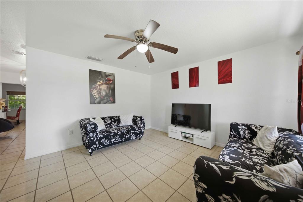 A living room features two floral sofas, a television on a white stand, and tile flooring — 3416 NE 22ND COURT, OCALA, FL