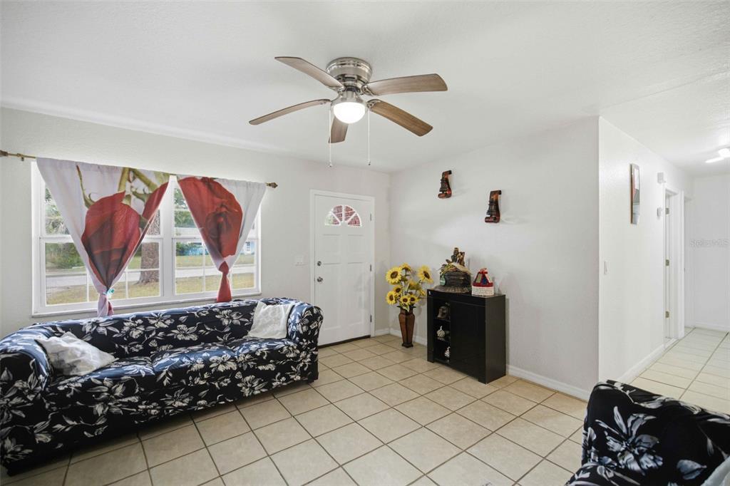 A living room features tile flooring, a floral sofa, a ceiling fan, and a front door — 3416 NE 22ND COURT, OCALA, FL
