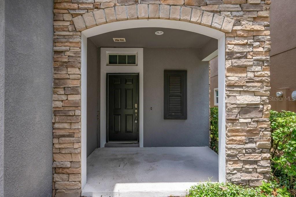 A covered entryway features a black front door, stone veneer columns, and an arched ceiling — 14306 BARRINGTON STOWERS DRIVE, LITHIA, FL