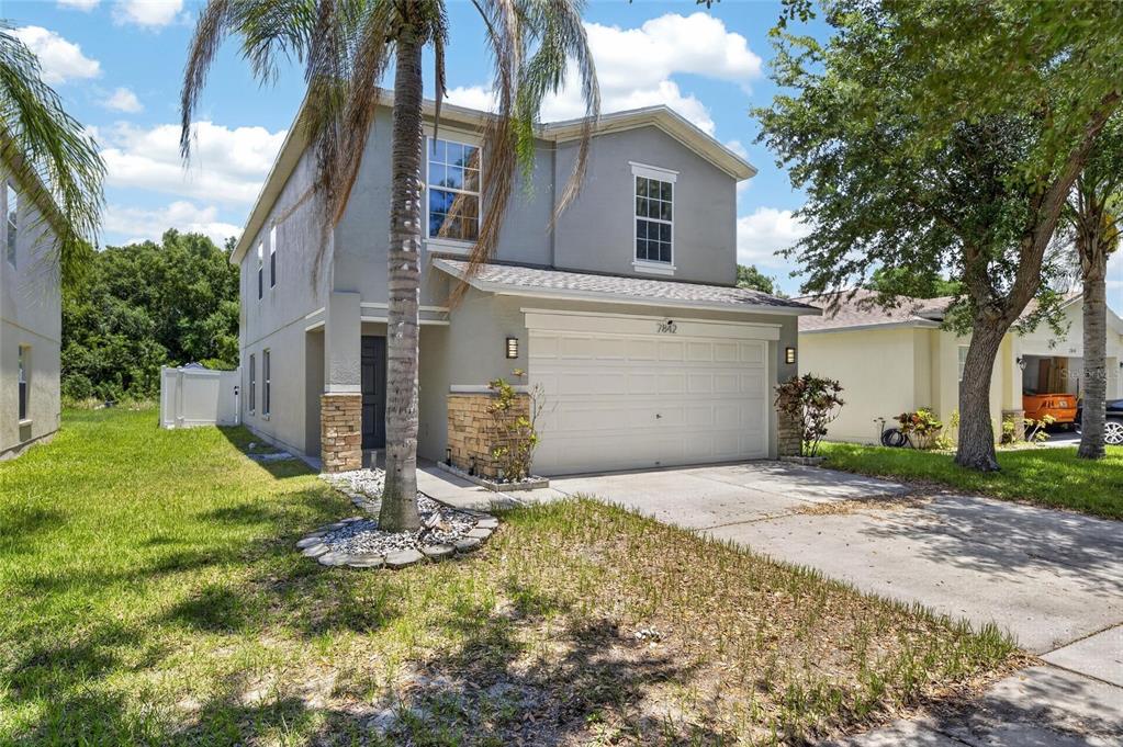 A two-story suburban house with a gray stucco exterior, stone accents, and a two-car garage — 7842 CARRIAGE POINTE DRIVE, GIBSONTON, FL