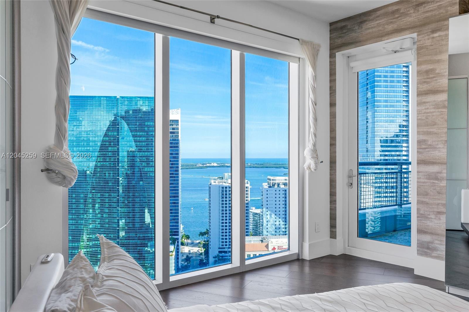 A bedroom features floor-to-ceiling windows with a city and ocean view and a balcony door — 60 SW 13th St # 3200, Miami FL 33130, MIAMI, FL