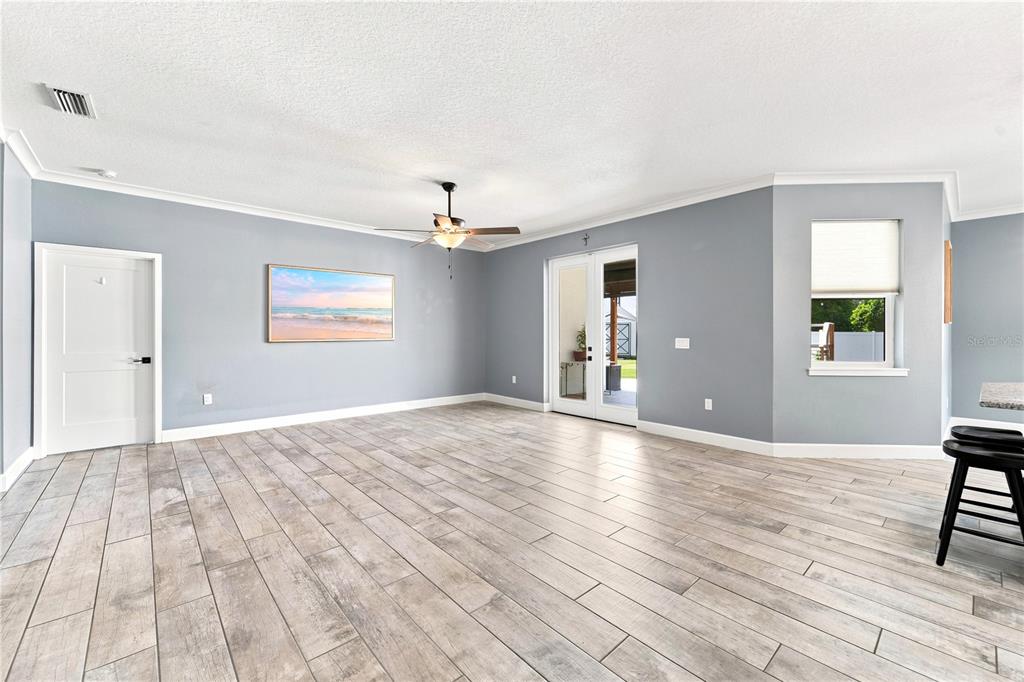 A living room with gray walls, wood-look tile flooring, a ceiling fan, and French doors — 125 LONGWOOD DRIVE, OSTEEN, FL
