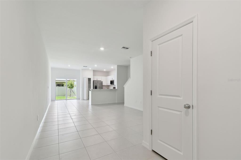A view of a white-walled interior with tile flooring, a closed door, and a kitchen — 2665 BUTTERCUP LUCINE LANE, RUSKIN, FL