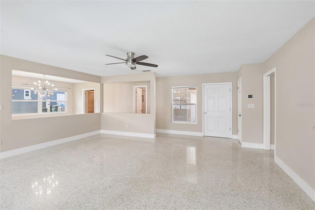 A bright, open-concept living room features light-colored walls, a ceiling fan, and polished terrazzo flooring — 563 EASTVIEW ROAD, LARGO, FL