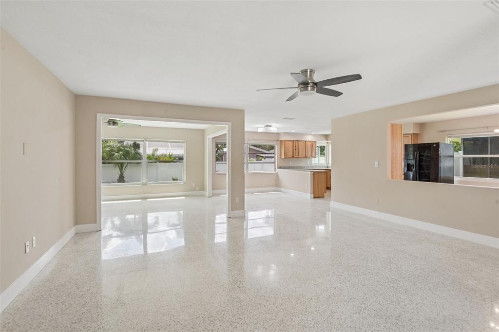 A spacious, open-concept living area features light-colored terrazzo flooring, neutral walls, and a ceiling fan — 563 EASTVIEW ROAD, LARGO, FL