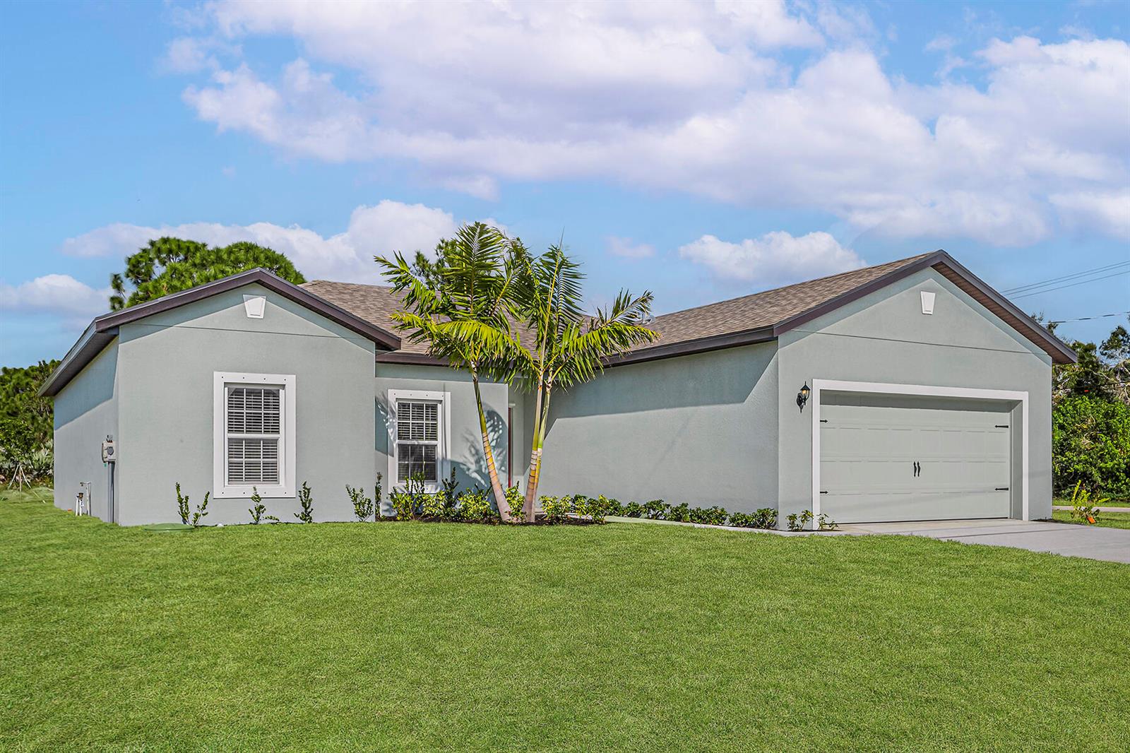A single-story house with light green stucco, a two-car garage, and a palm tree — 8446 104th Court, Vero Beach FL 32967, VERO BEACH, FL