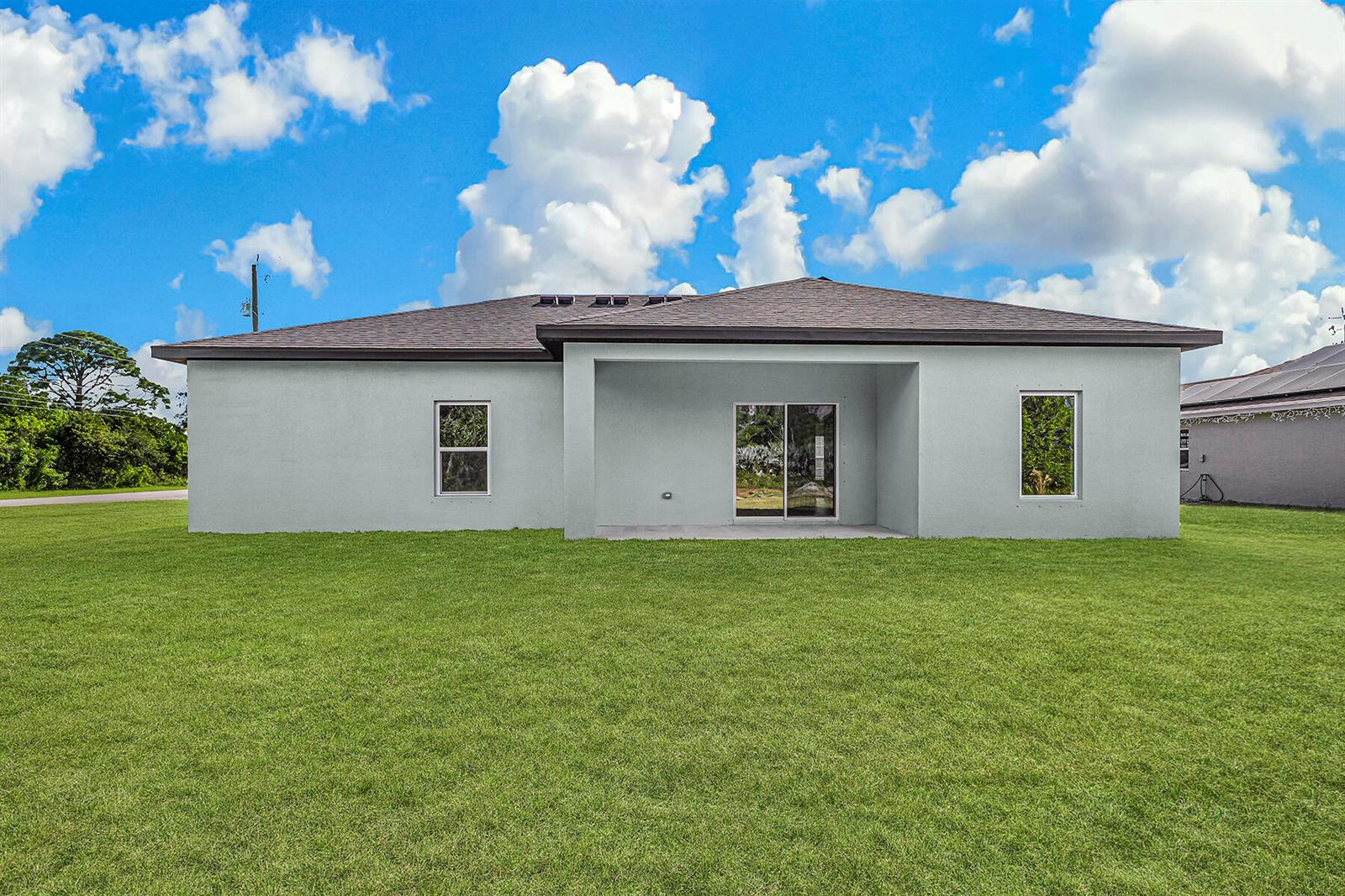 The rear exterior of a single-story house features a covered patio and a grassy yard — 8446 104th Court, Vero Beach FL 32967, VERO BEACH, FL