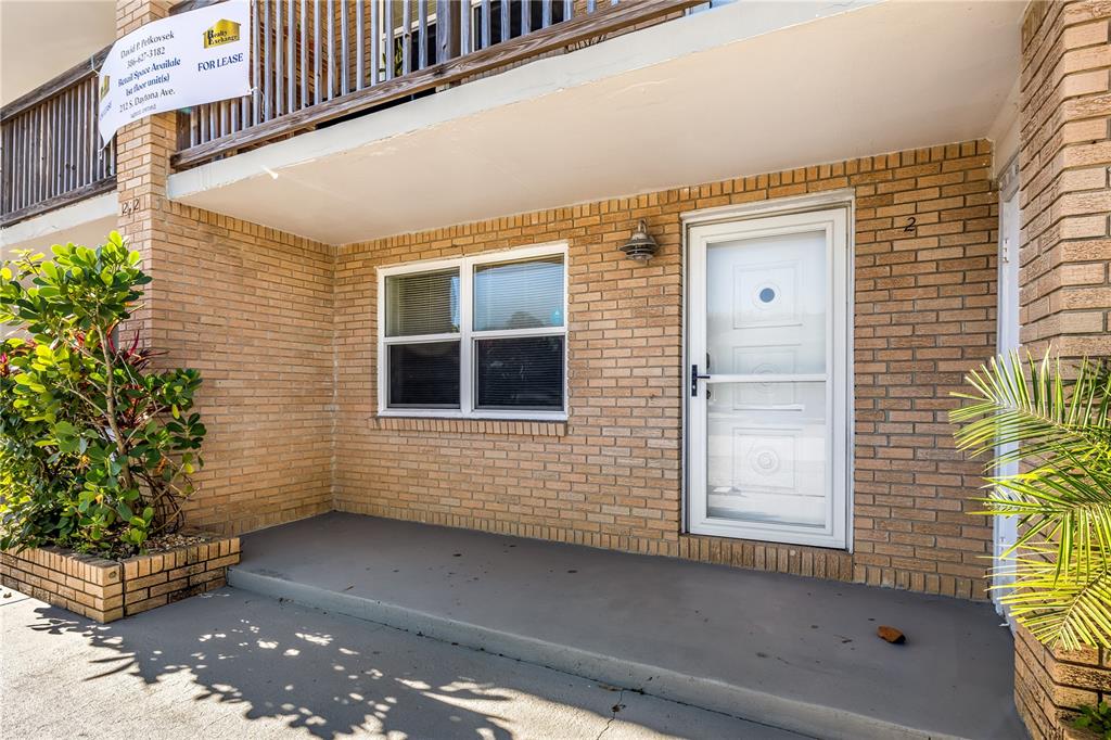 A brick building exterior features a white front door, a window, and a concrete porch — 212 S DAYTONA AVENUE UNIT 2, FLAGLER BEACH, FL