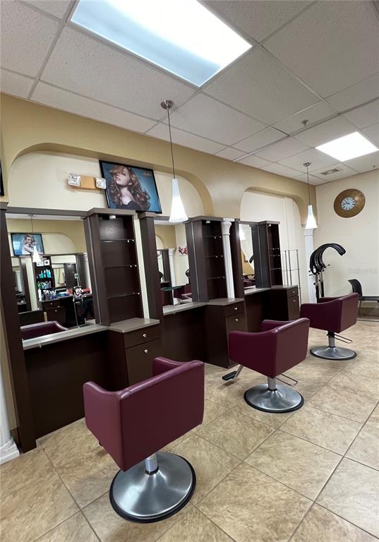 A hair salon features three styling stations with large mirrors, dark cabinetry, and burgundy chairs — 319 WEST ROAD, OCOEE, FL