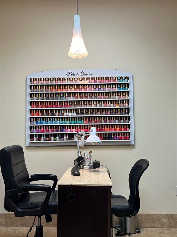 A nail salon station features a wall-mounted polish display rack, a desk, and two chairs — 319 WEST ROAD, OCOEE, FL