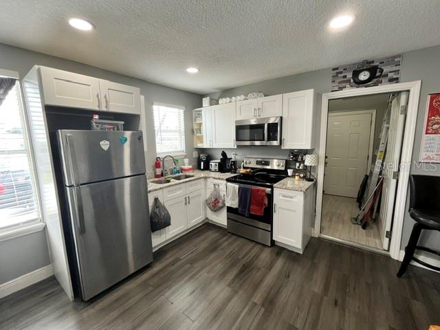 A kitchen features white cabinets, stainless steel appliances, and dark wood-look flooring — 118 W STUART AVENUE, LAKE WALES, FL