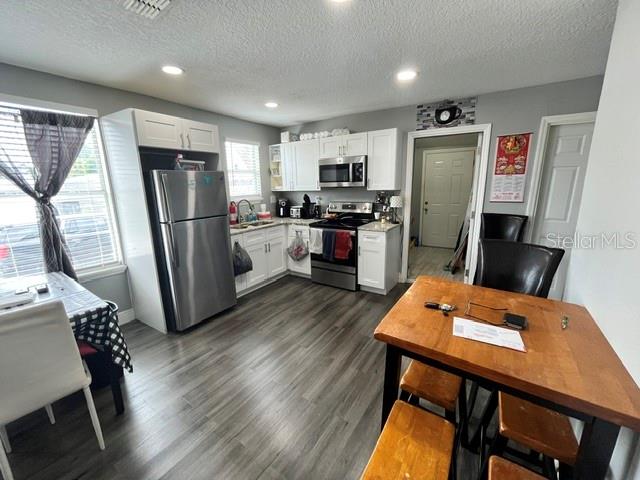 A kitchen features stainless steel appliances, white cabinetry, and wood-look flooring — 118 W STUART AVENUE, LAKE WALES, FL
