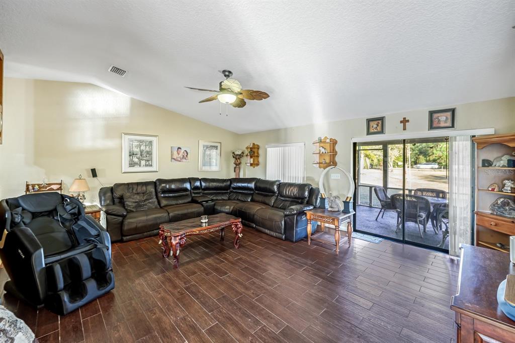 A living room features dark wood-look tile flooring, a large sectional sofa, and a sliding door — 16321 SLATER ROAD, NORTH FORT MYERS, FL