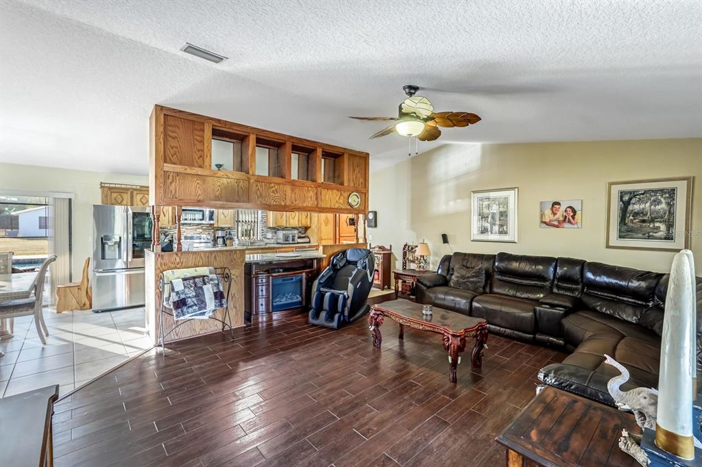 A living room with dark wood flooring, a leather sectional, and a wooden room divider — 16321 SLATER ROAD, NORTH FORT MYERS, FL