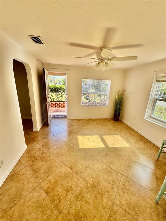 A room with light-colored walls, tile flooring, a ceiling fan, and an open exterior door — 910 W FRENCH AVENUE, ORANGE CITY, FL