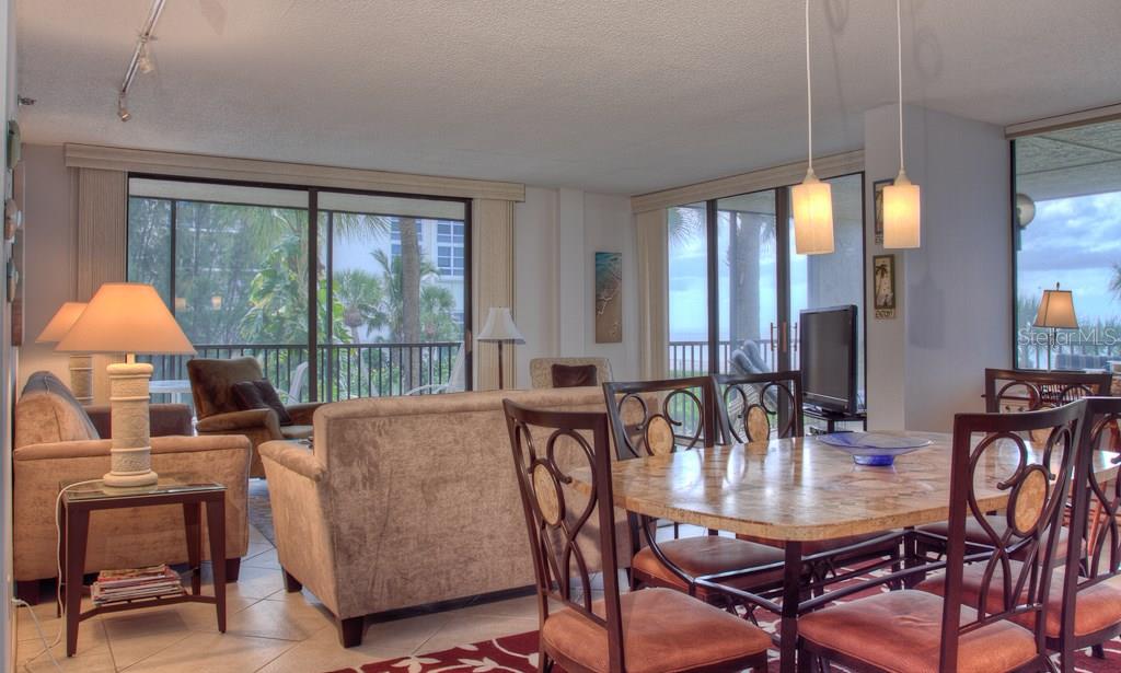 A living and dining area features tile floors, a stone table, and large sliding glass doors — 1925 GULF OF MEXICO DRIVE UNIT G8-208, LONGBOAT KEY, FL