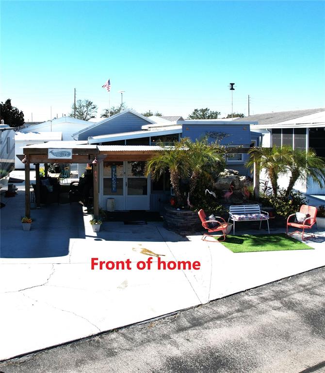 A mobile home exterior features a covered patio, palm trees, and outdoor seating — 411 ST GEORGE DRIVE, DAVENPORT, FL