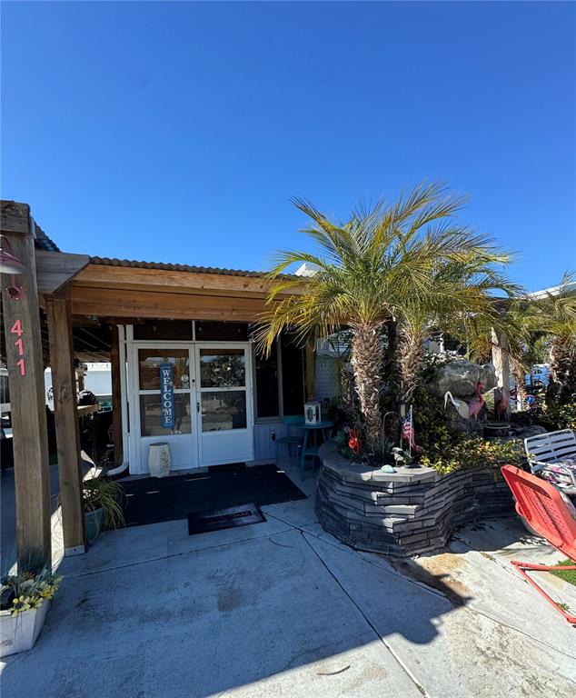 A covered patio features a white door, a stone planter with a palm tree, and furniture — 411 ST GEORGE DRIVE, DAVENPORT, FL