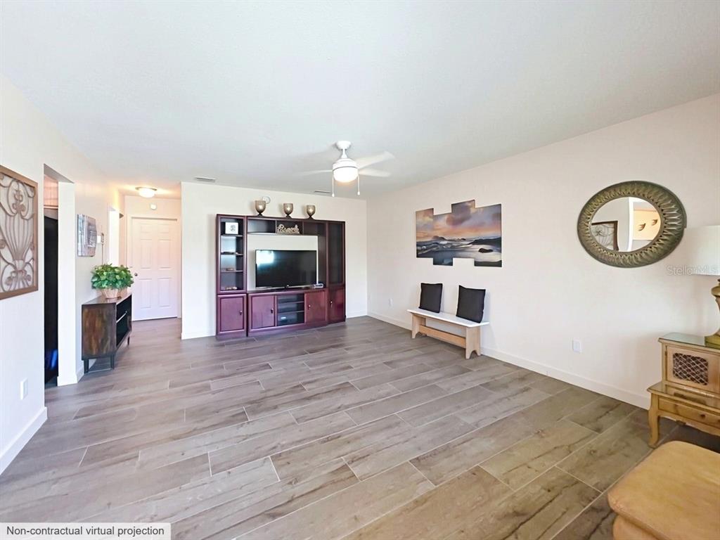 This living room features wood-look tile flooring, a ceiling fan, and a dark wood entertainment center — 400 OAKRIDGE BOULEVARD UNIT 60, DAYTONA BEACH, FL