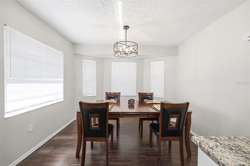 A dining room features a dark wood table, four chairs, and a modern chandelier — 5552 W IRVING COURT, HOMOSASSA, FL
