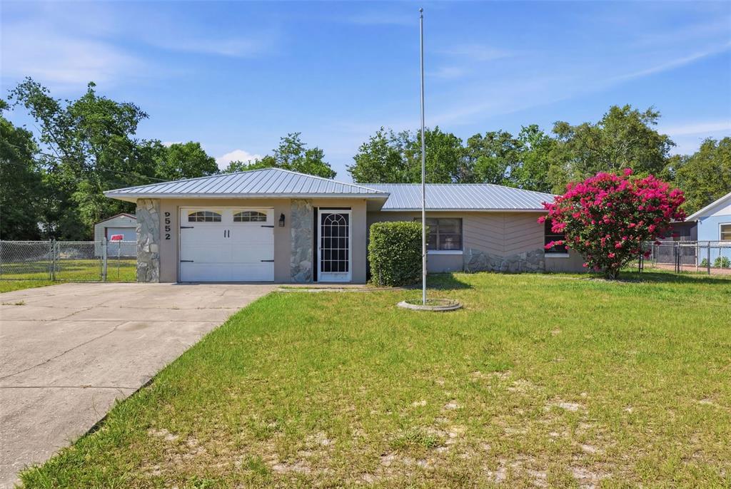 A single-story house with a metal roof, stone accents, and a concrete driveway — 5552 W IRVING COURT, HOMOSASSA, FL