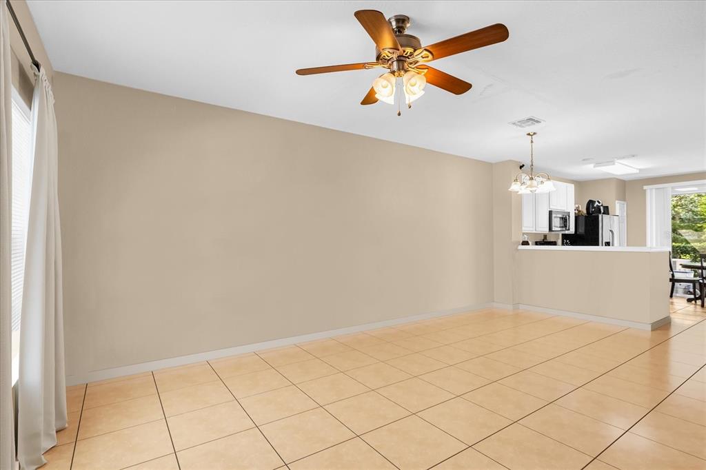 A dining area with beige walls, tile flooring, a ceiling fan, and an open kitchen — 727 SHROPSHIRE LOOP, SANFORD, FL