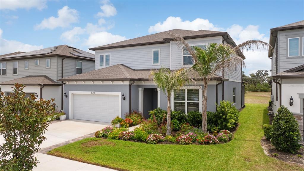 A two-story house with gray siding, a white garage door, and a landscaped front yard — 11490 CALUSA TRAILS WAY, RIVERVIEW, FL